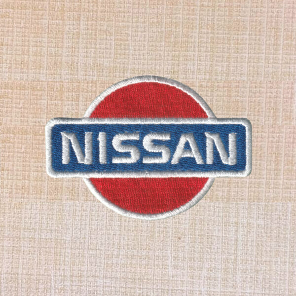 Nissan logo embroidered iron-on patch in silver, black, and red for automotive apparel.