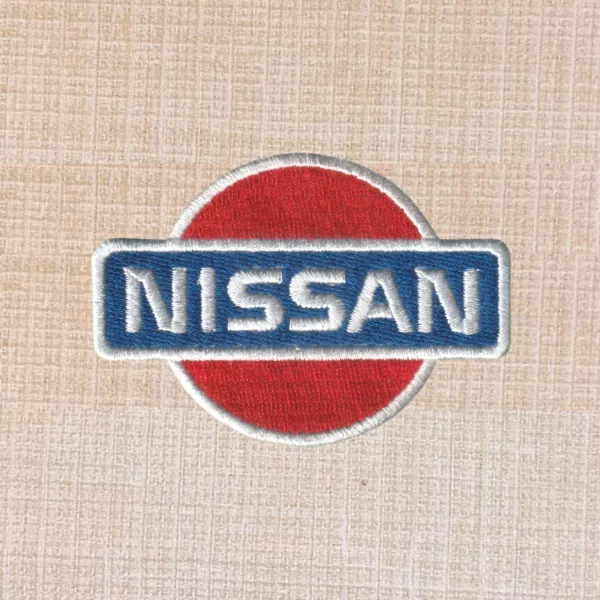 Nissan logo embroidered iron-on patch in silver, black, and red for automotive apparel.