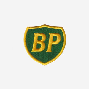 BP logo embroidered iron-on patch in green and yellow on denim surface with merrowed edge